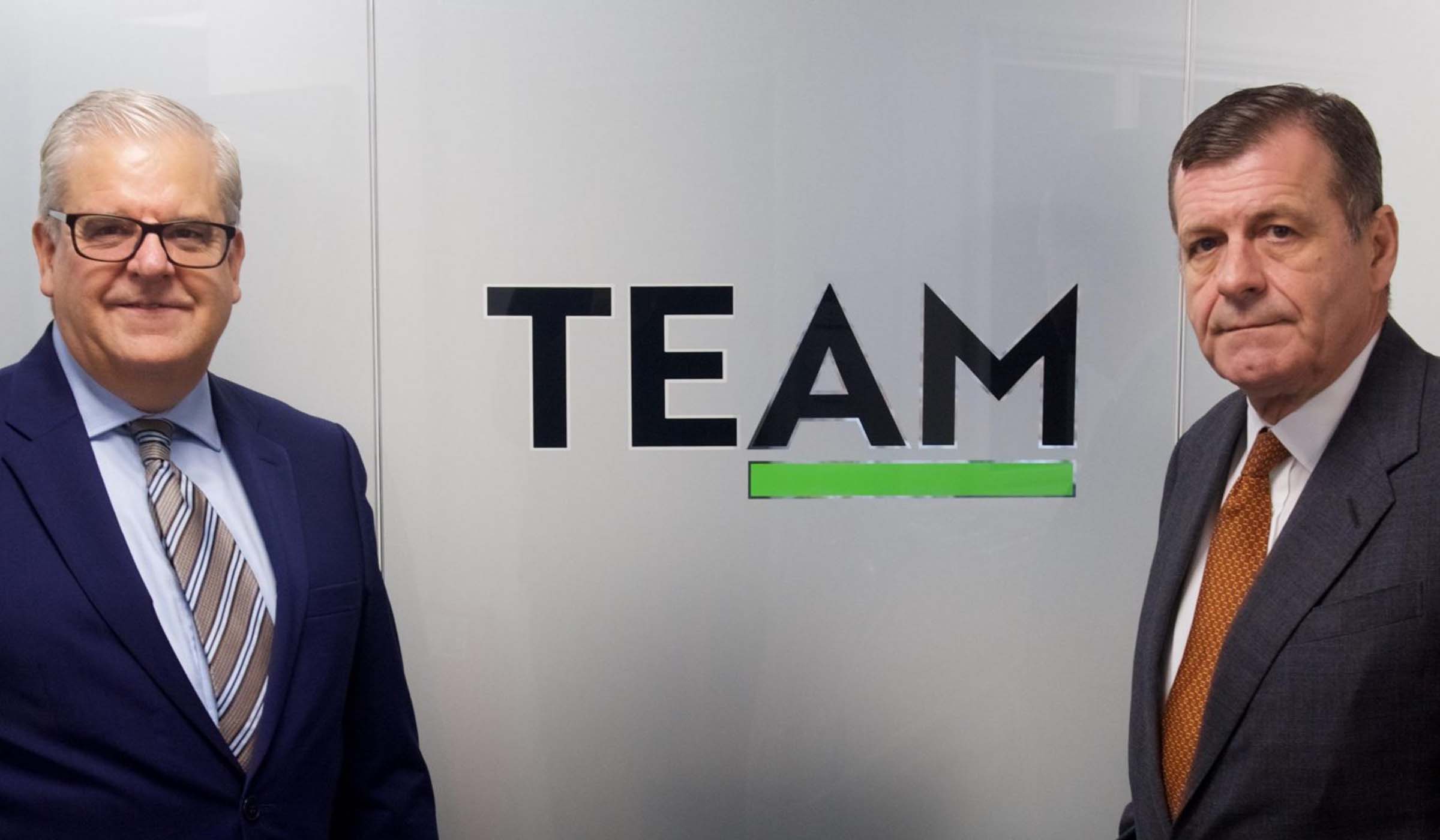 TEAM representatives in front of the TEAM logo