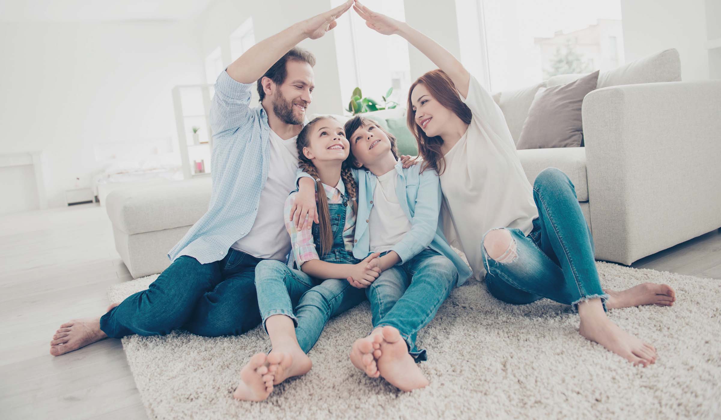 Family sitting together under a roof formed by their hands