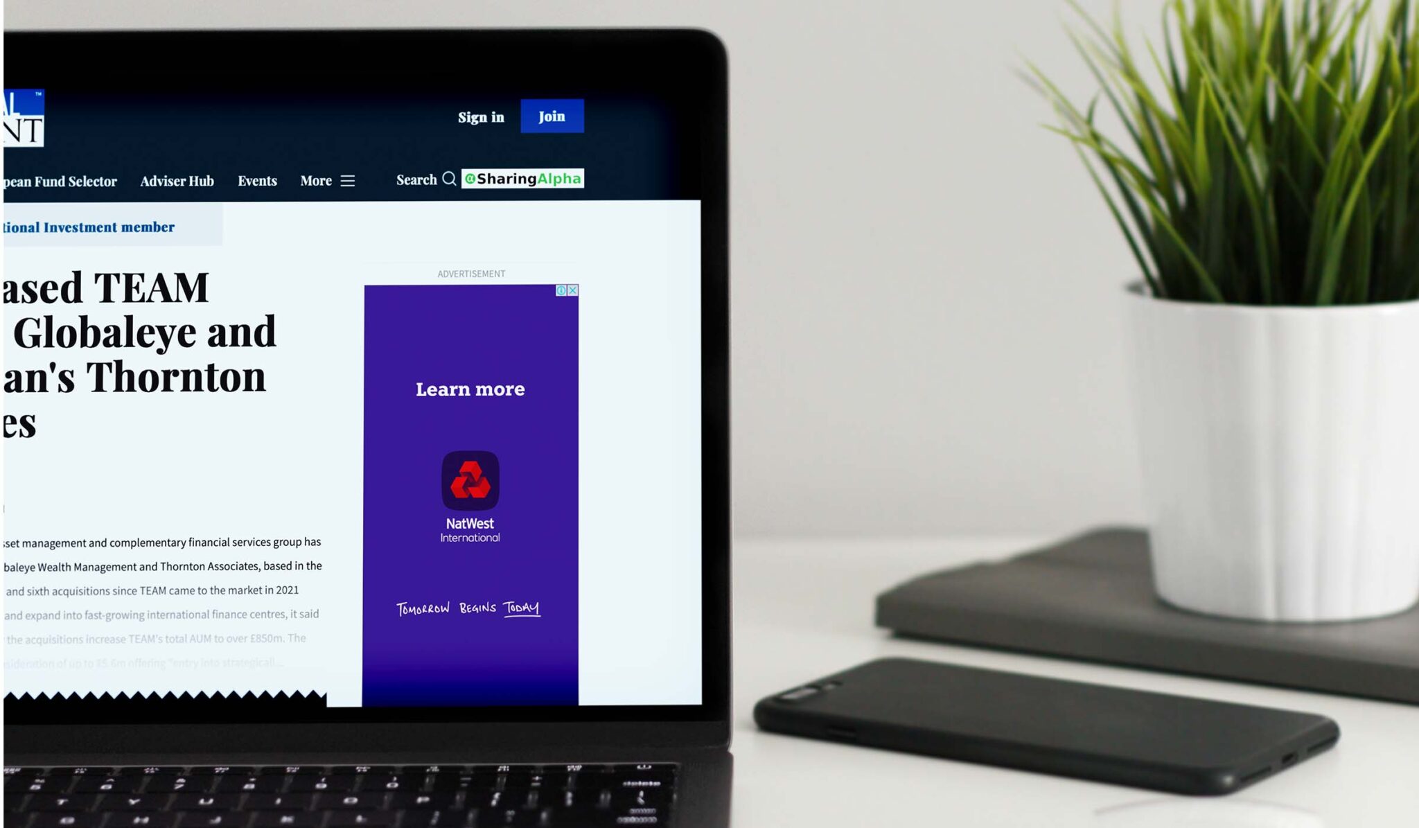 Laptop showing International Investment coverage of TEAM acquiring NEBA Financial Solutions