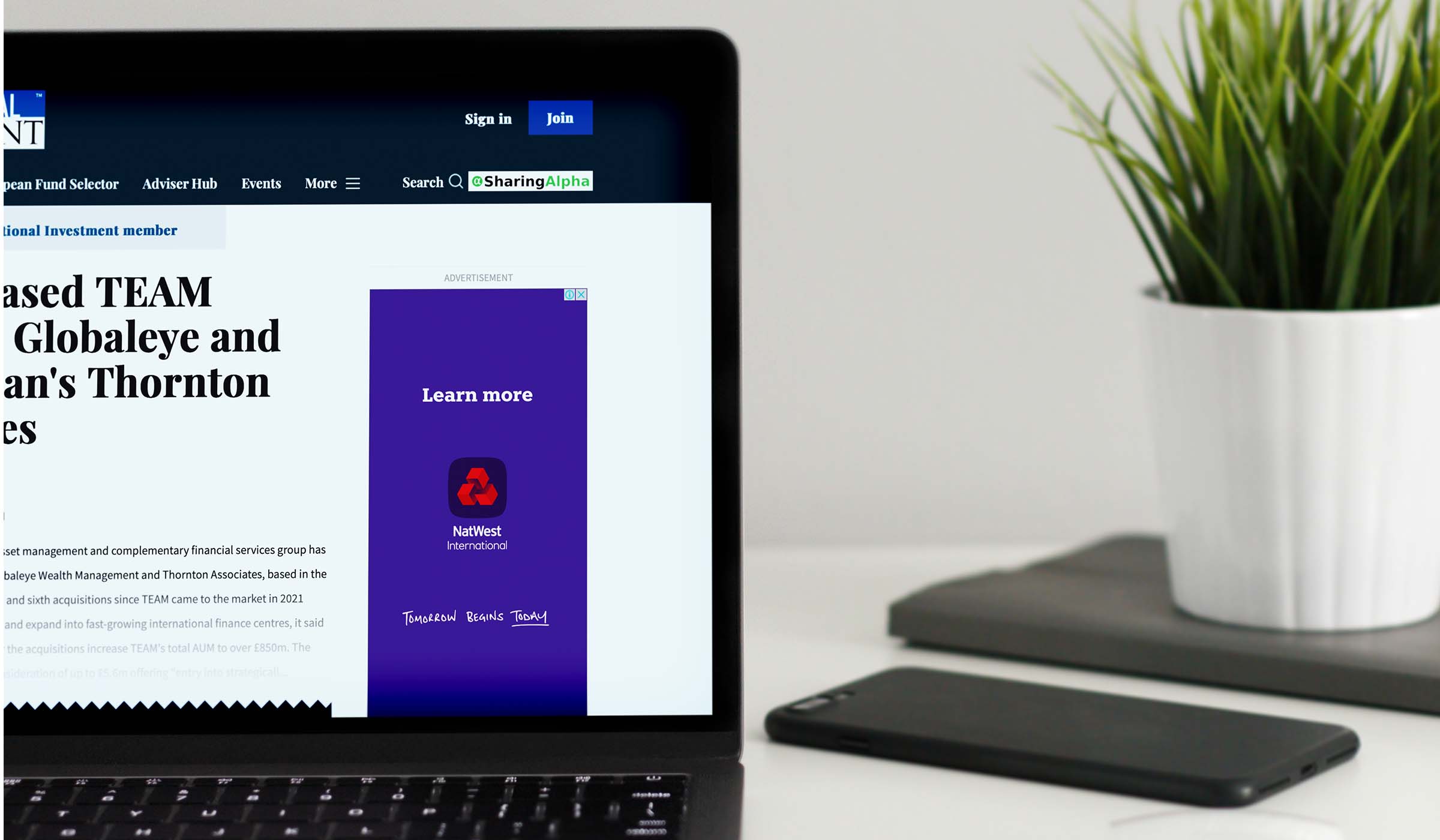 Laptop showing International Investment coverage of TEAM acquiring NEBA Financial Solutions